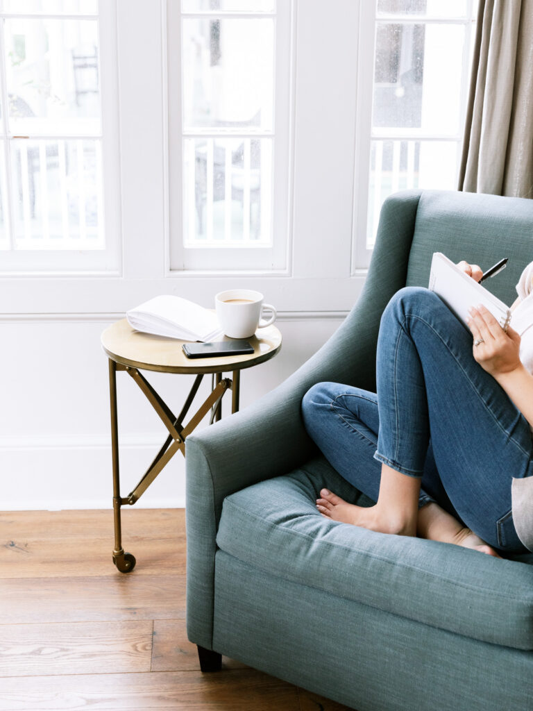 woman writing on a chair with a notebook on lap