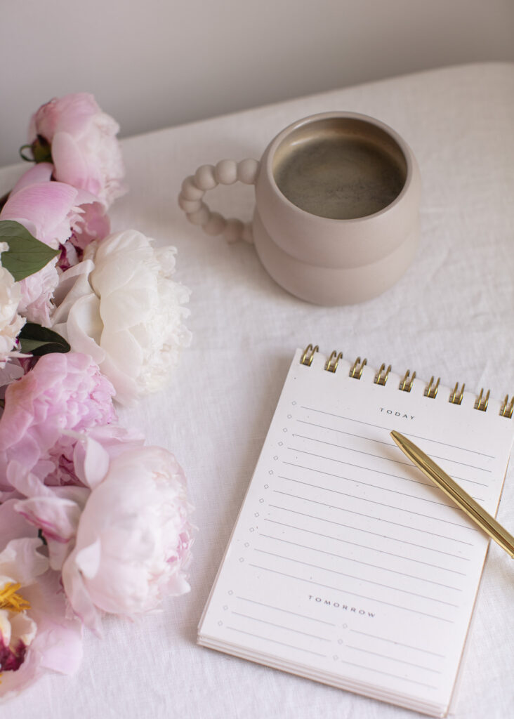 A notebook on a desk next to flowers