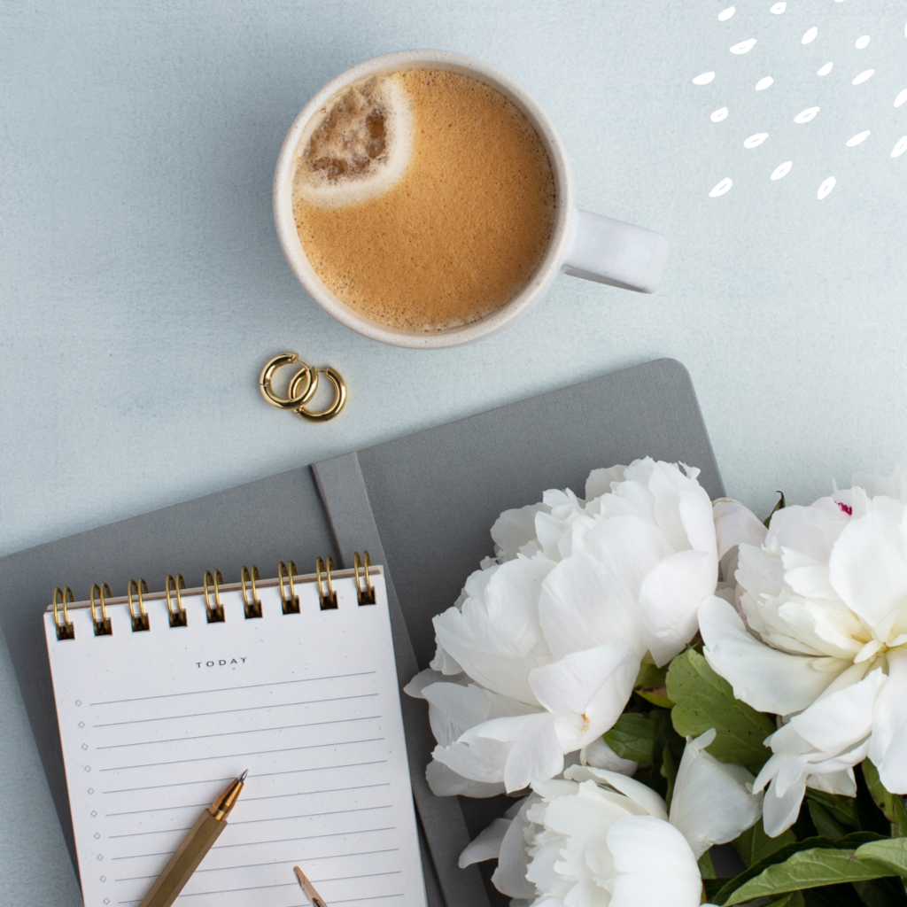 A coffee mug, notebook and pen on a desk